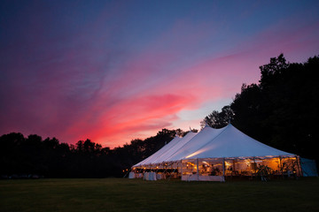 an event tent at night with a sunset during a wedding