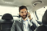 Fototapeta  - Casual business man on mobile phone in rear of the car
