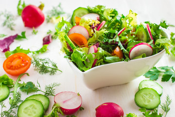 Healthy salad with fresh vegetables and ingredients on white bac