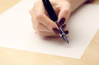 © Africa Studio - Female hand writing letter on white sheet of paper by fountain pen on wooden table background