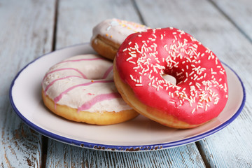 Poster - Delicious donuts with icing on plate on wooden background