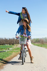 Wall Mural - Two beautiful young women with a vintage bike in the field.