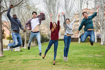 Group of young people jumping together outdoors