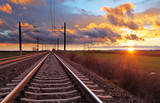 Fototapeta  - Orange sunset in low clouds over railroad