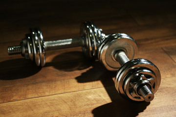 Canvas Print - Dumbbells on wooden floor, on dark background