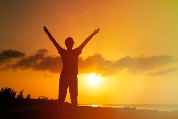 man with his hands up on sunset beach