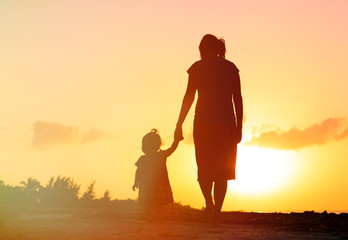 mother and little daughter walking at sunset