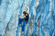 © vitaliymateha - Rock climber climbing up a cliff