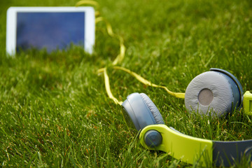 white tablet and headphones lying on the grass