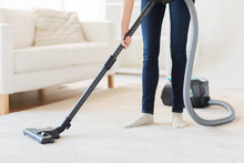 Close Up Of Woman Legs With Vacuum Cleaner At Home