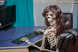 Joyful smiling skeleton in a wig sitting in chair