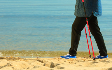 active woman senior nordic walking on a beach. legs