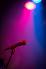A Band Stage Microphone Highlighted By A Pink And Blue Light
