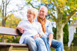 © Kzenon - Senioren Paar sitzt im Herbst auf Parkbank