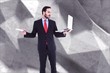 © WavebreakMediaMicro - Composite image of handsome businessman holding his laptop