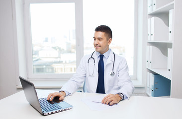 Wall Mural - smiling male doctor with laptop in medical office