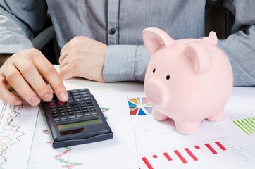 Wall Mural - Man calculates money. Piggy bank and business documents on desk