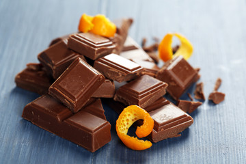Wall Mural - Pieces of chocolate with orange peels on wooden background