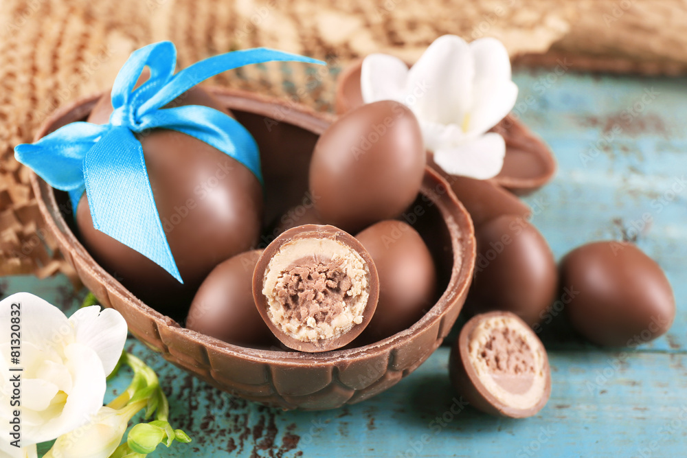 Chocolate Easter eggs with flowers on wooden table, closeup