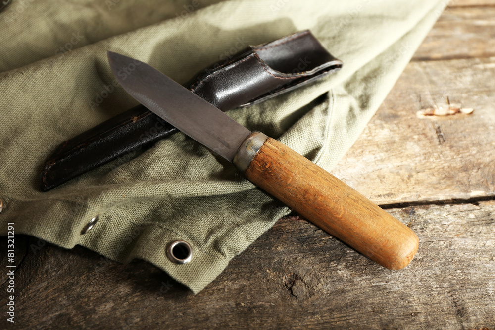 Hunting knife and sackcloth on wooden background