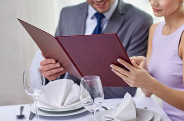 Wall Mural - close up of happy couple with menu at restaurant