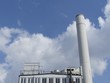 Altes Heizkraftwerk zur Wärmegewinnung mit weißem Schornstein vor blauem Himmel mit Wolken im Sonnenschein in der Innenstadt von Frankfurt am Main in Hessen