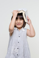 Wall Mural - Portrait of little Asian child put a book on top