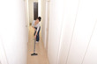 © beeboys - 笑顔でマンションの部屋に掃除機をかけているアジア人の綺麗な女性