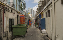 A Back Ally In Singapore. With Stacks Of Crates And Wheel Bins