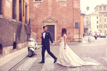 Bride And Groom Walking On Paved Road
