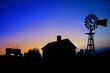 Silhouette of a farm tractor, house and windmill.