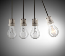 Light Bulbs In Row With Single One Shinning