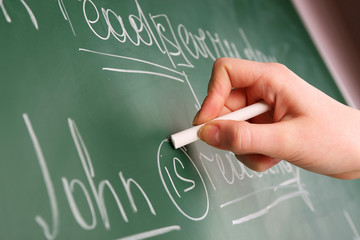 Wall Mural - Teacher hand writing grammar sentences on blackboard background