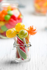 Wall Mural - Colorful candies in jars on table on light background