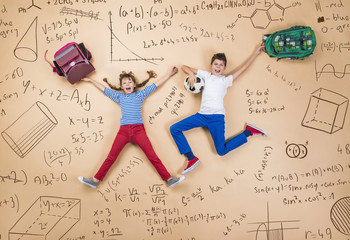 Cute boy and girl learning playfully in frot of a big blackboard