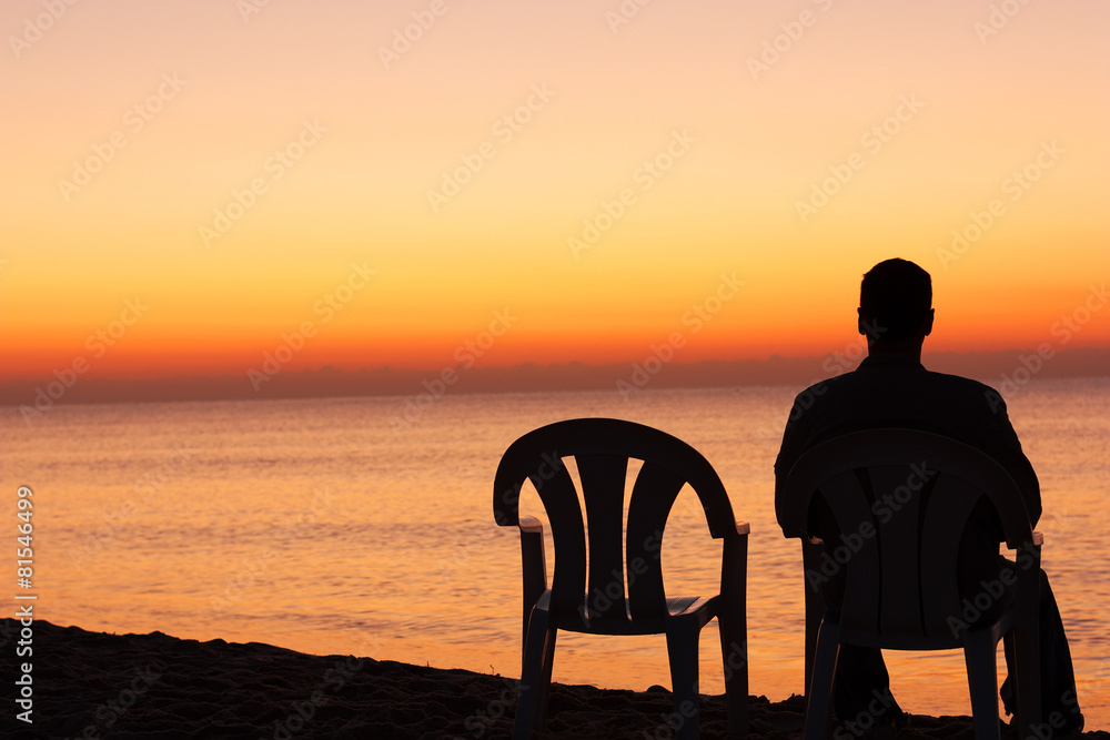 Man sits on chair alone in sunset - obrazy, fototapety, plakaty 
