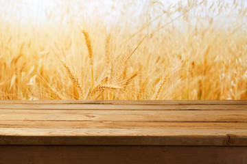 Wall Mural - Empty wooden table over wheat field background