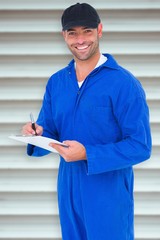 Poster - Composite image of handyman in blue overall writing on clipboard