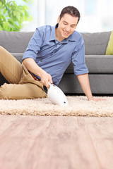 Canvas Print - Man cleaning his carpet with a handheld vacuum cleaner