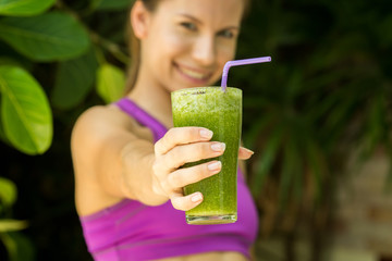 Athletic girl holding a green smoothie