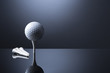 © lichtmeister - Golf ball on tee isolated on dark blue reflective background.