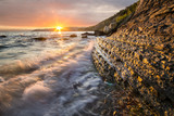 Fototapeta Fototapety z morzem do Twojej sypialni - Dynamiczny wschód słońca nad skalistym wybrzeżem morskim