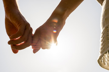 couple hands holding together with sun rays