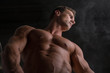 © theartofphoto - Low angle shot of shirtless male bodybuilder on dark background