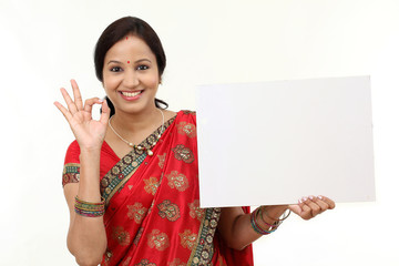 Wall Mural - Traditional woman holding a blank billboard and making ok gestur