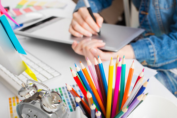 young woman artist in jeans jacket drawing something on graphic