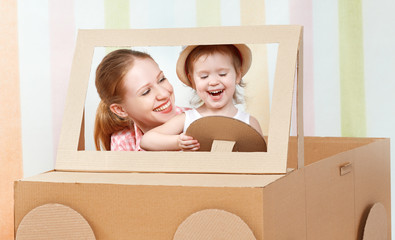 Wall Mural - Happy family mother and little daughter ride on toy car made of