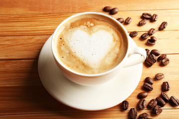 Canvas Print - Cup of coffee latte art with grains on wooden table, closeup