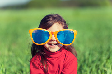 Happy smiling little girl wearing big sunglasses