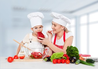 Wall Mural - Adorable. Mother feeding kid daughter vegetables in kitchen